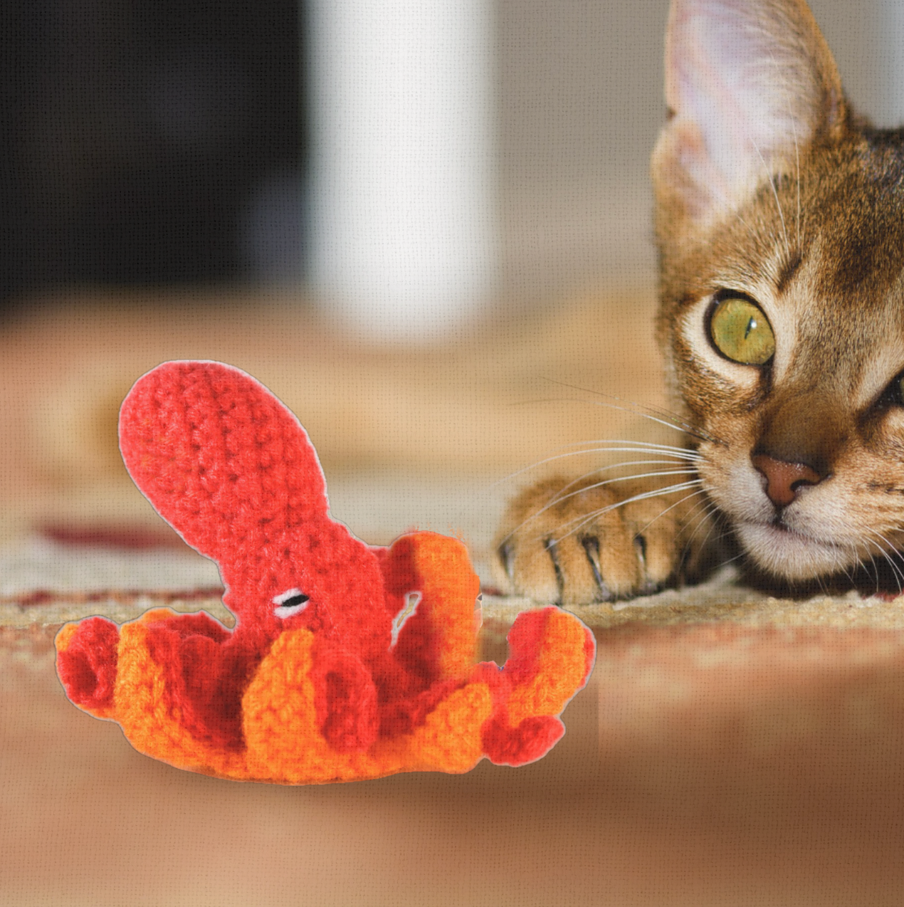 Cat ready to pounce on Julie the Kraken, a handmade Chunkle Puff catnip toy. The 6 inch octopus-inspired design trails dramatically as it is batted and tugged by a cat.