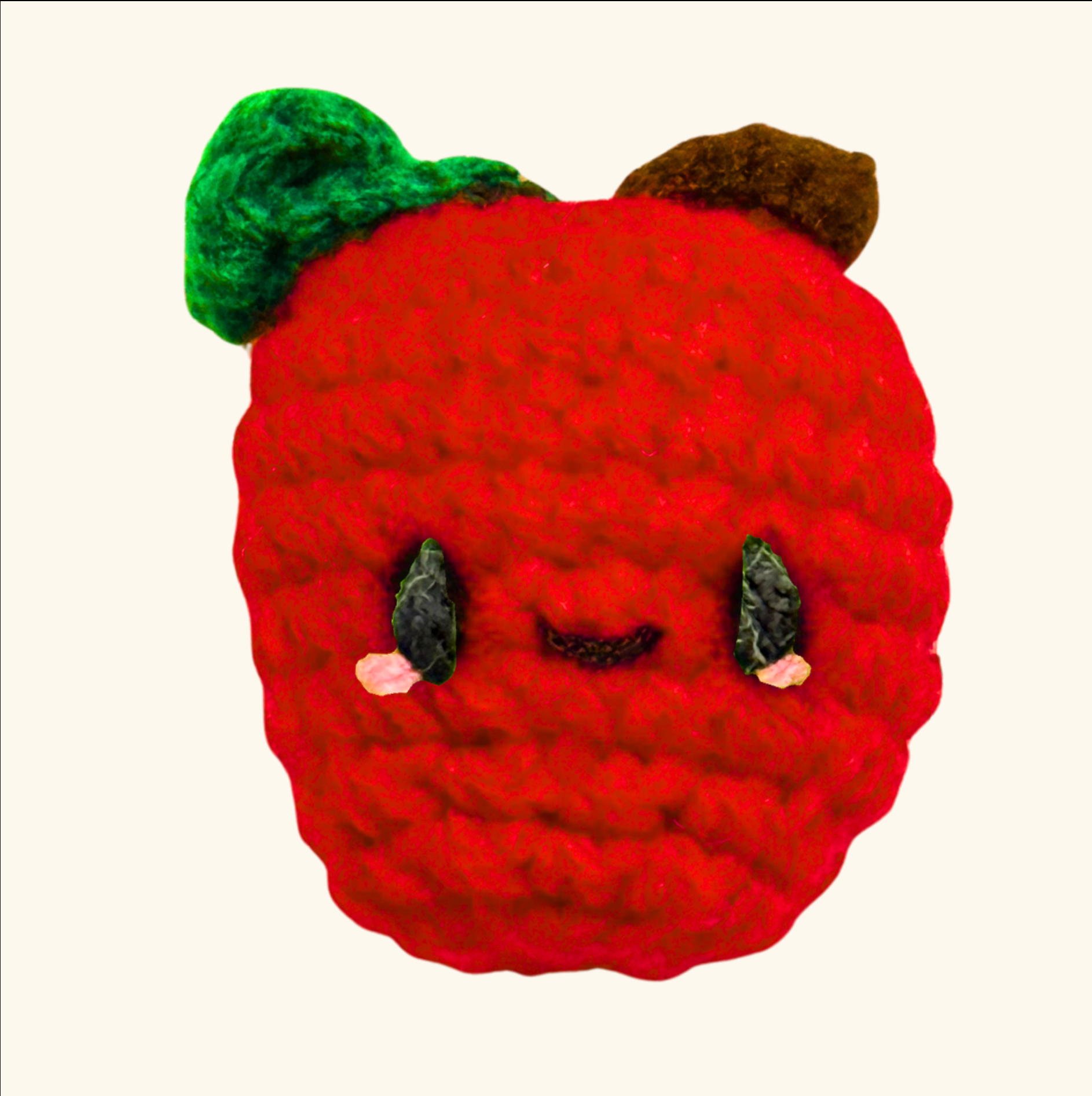 Crocheted red apple with a face on a white background to represent apple shaped Chunkle catnip toy infused with Miracle Nip botanicals by Minou Le-Mew