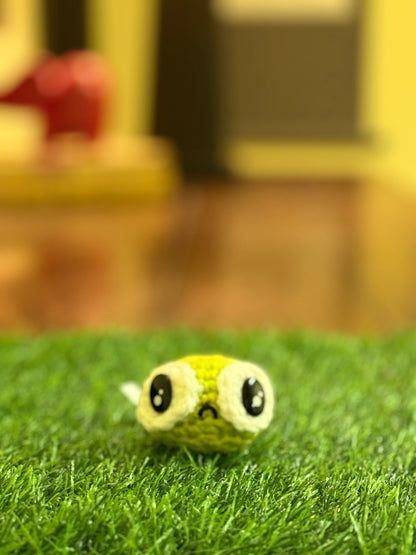 A hilariously adorable snapshot of Cranky Pea Steve, the green Chunkle Puff artisan cat toy with a perpetually grumpy little face. This tiny crocheted masterpiece features oversized, expressive eyes and a slightly downturned mouth, radiating maximum pouty vibes. Set against a soft grass backdrop with a cozy, blurred indoor ambiance, Steve’s unique personality shines through. Lightweight for delightful cat play, Steve is sure to be your feline’s favorite companion for a bit of sassy fun!