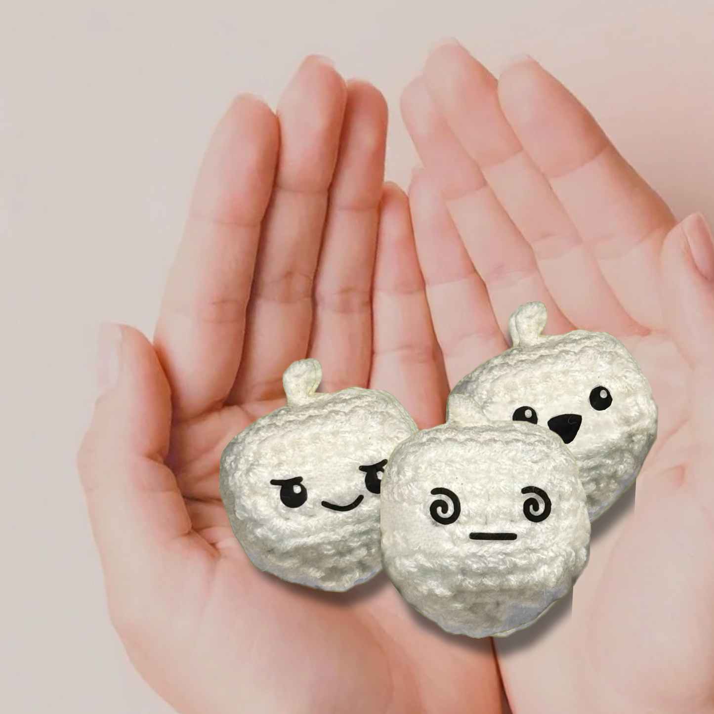 Three small dreidel toys with faces held in hands against a light pink background to represent Chunkle catnip toy infused with Miracle Nip botanicals by Minou Le-Mew