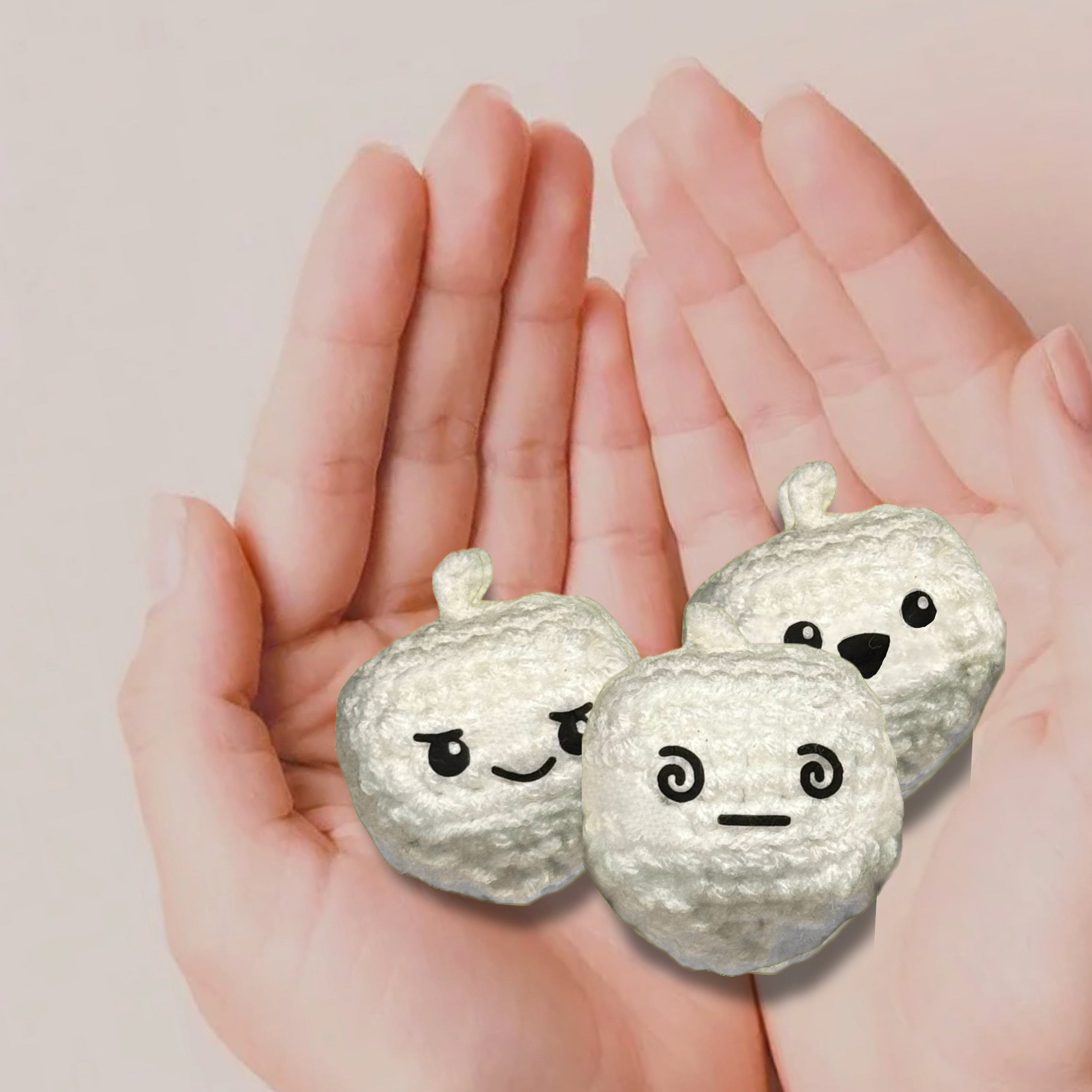 Three small dreidel toys with faces held in hands against a light pink background to represent Chunkle catnip toy infused with Miracle Nip botanicals by Minou Le-Mew