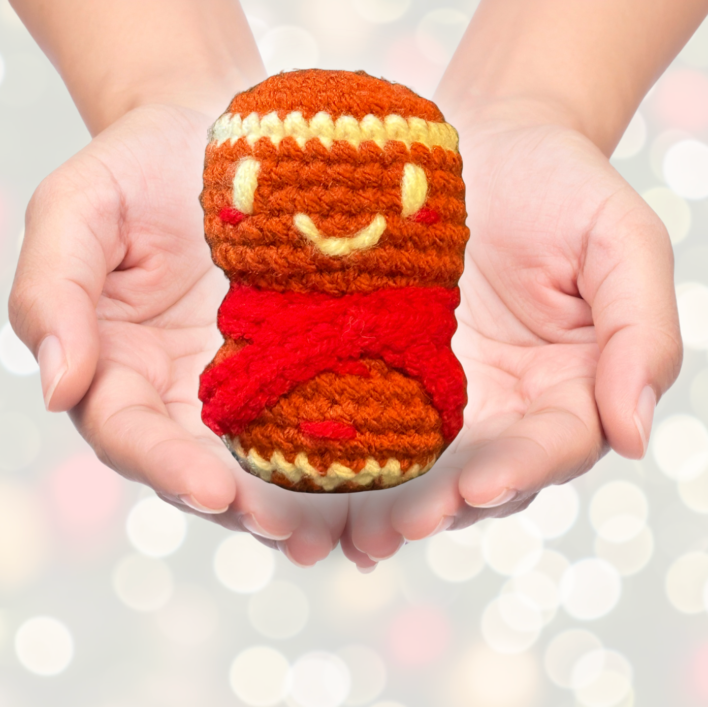 Artisan crocheted cat toy resembling a cupcake with a smiling face held in hands against a blurred light background to represent Minou Le-Mew artisan Chunkle catnip toy infused with Miracle Nip botanicals