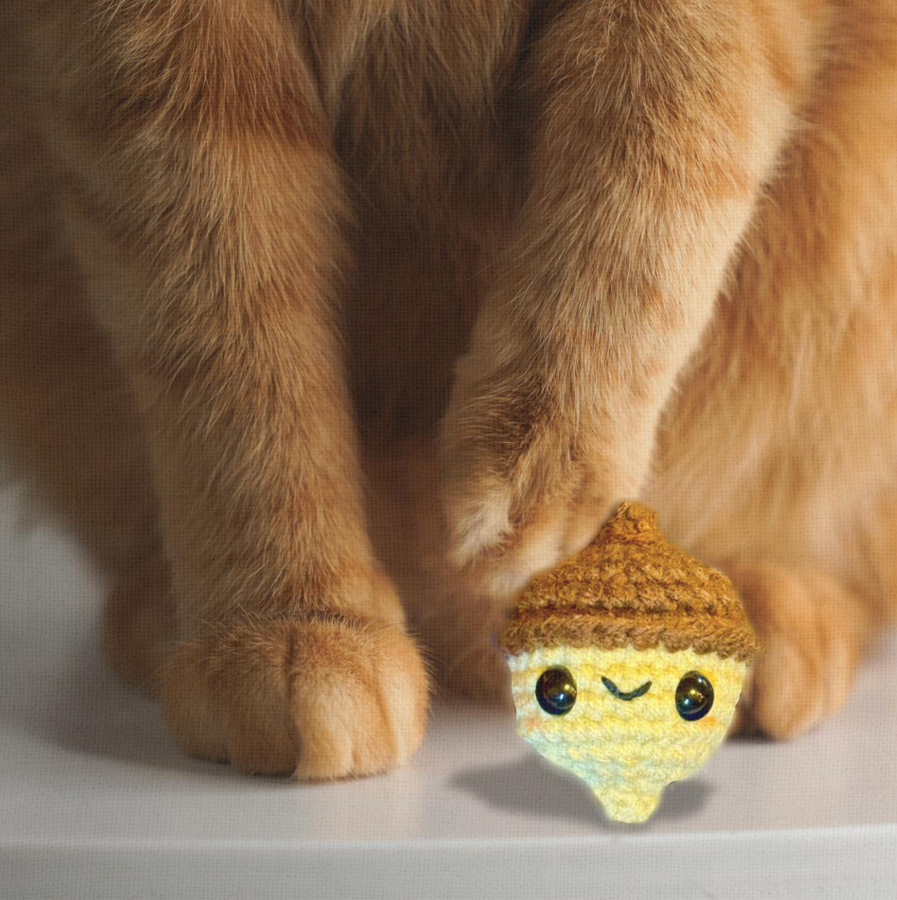 Augie the Acorn, a handmade catnip toy, shown beside a hand for scale. Rounded 3.5 inch Chunkle Puff design is easy for cats to bat, chase, and carry.