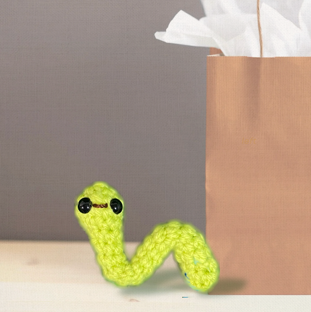Noodle the Inchworm, a handmade Chunkle Puff catnip toy by Feline Grove, shown with a boutique gift box. The elongated woven form is presented as a luxury collectible piece for refined gifting.