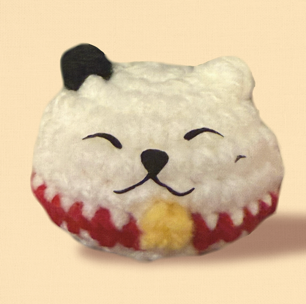 Plush cat toy shaped like a lucky cat with a happy expression on a beige background