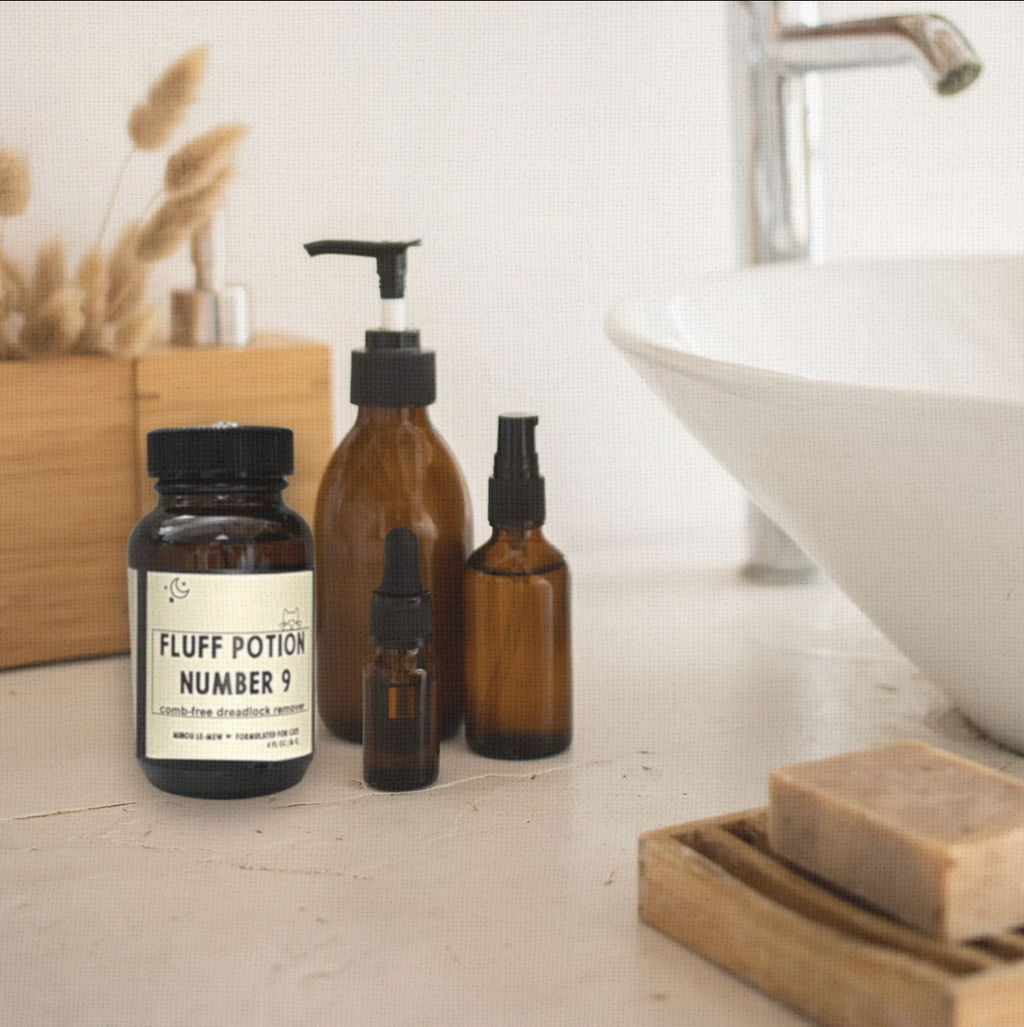 Fluff Potion Number 9, a 4 fl oz amber glass bottle, styled with other amber glass bottles soft lighting. An elegant grooming essential for refined cat care.