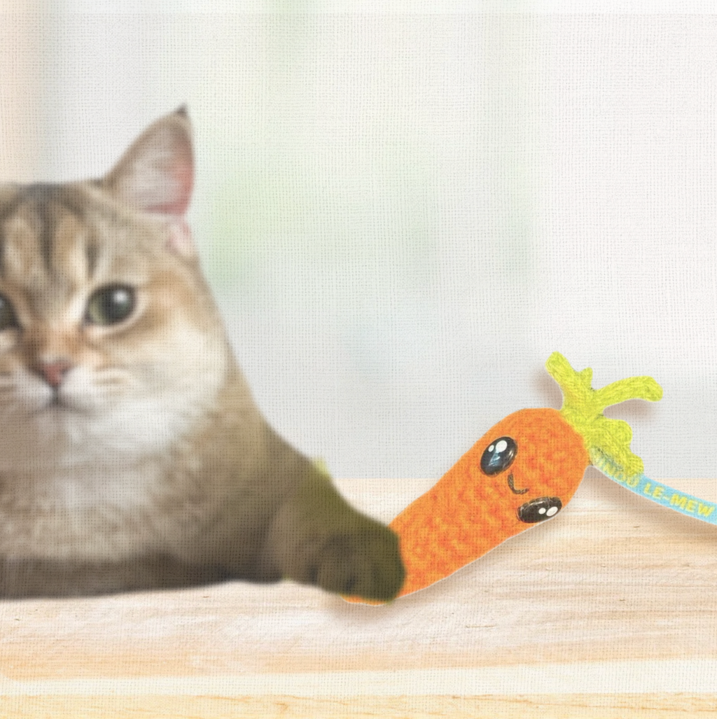 Lulu the Carrot, a 3.5 inch handmade catnip toy, shown beside a hand for scale. The woven Chunkle Puff design combines playful size with boutique elegance.