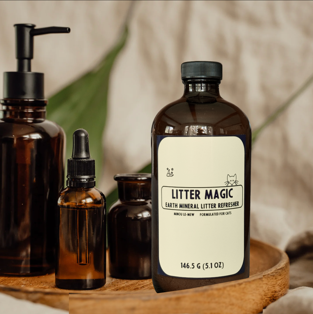 Litter Magic shown with other Minou Le-Mew amber glass cat care products. A boutique collection of luxury grooming and home essentials crafted with scientific expertise.