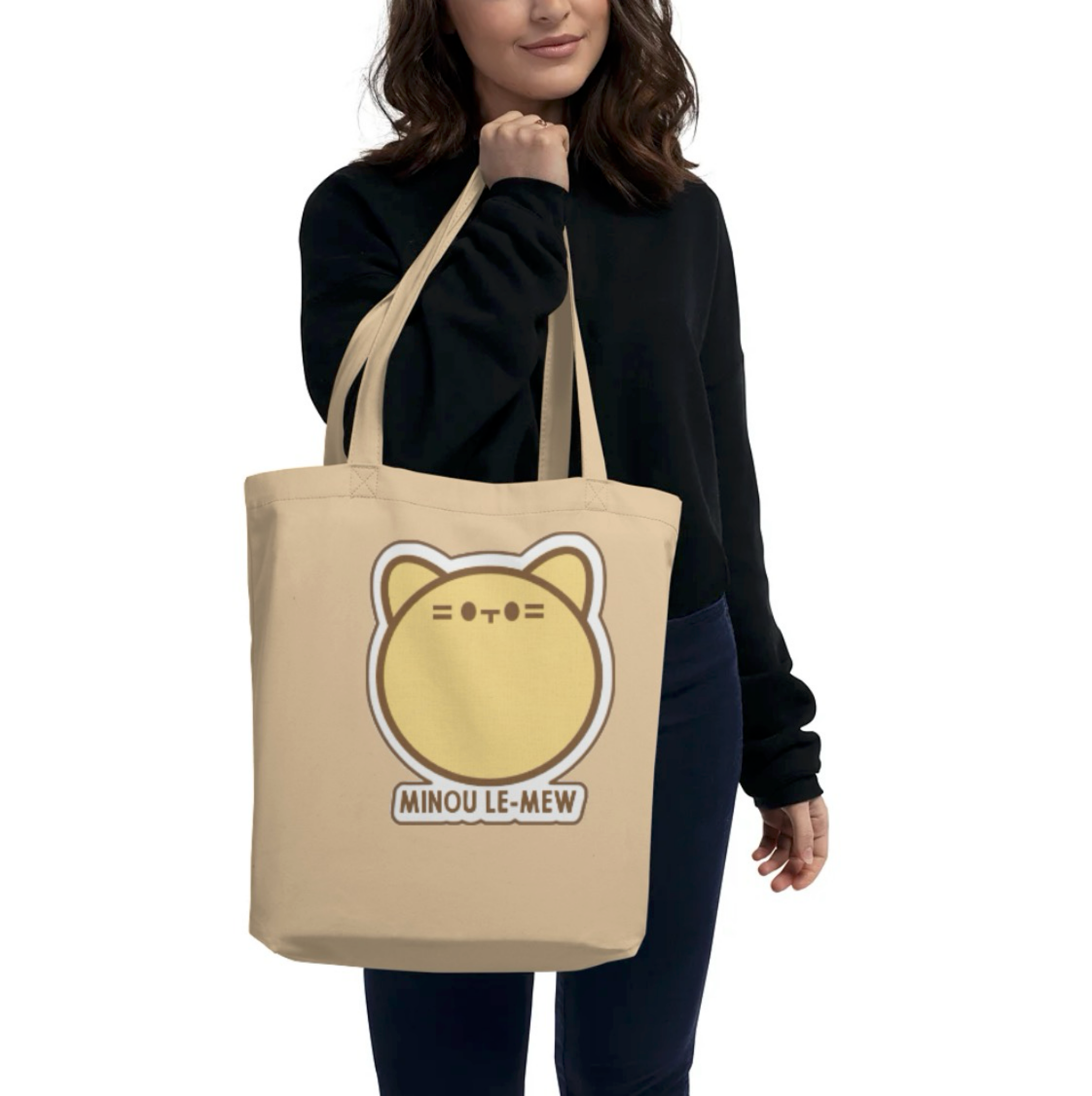 Person holding a beige tote bag with a cat graphic and text on a white background